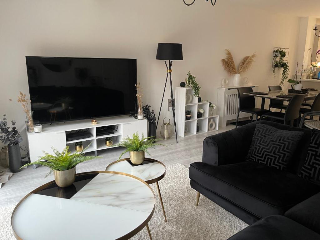 uma sala de estar com uma televisão, um sofá e mesas em Cosy Bedrooms em Manchester
