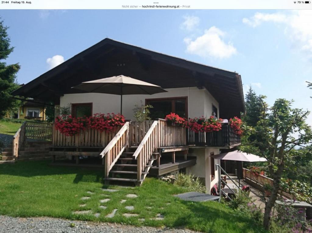 Casa con balcón con sombrilla y flores en Haus Weitblick, en Sirnitz-Sonnseite