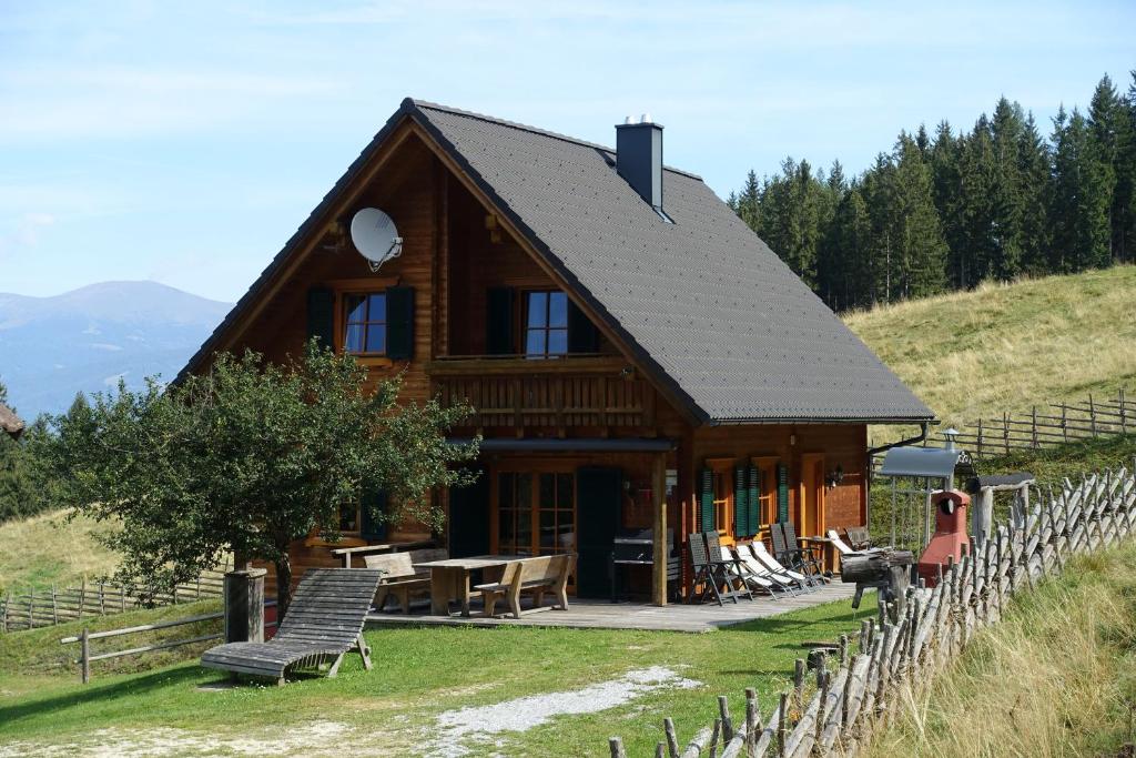 una casa de madera en una colina con mesa y sillas en Gerstbreinhütte en Bad Sankt Leonhard im Lavanttal