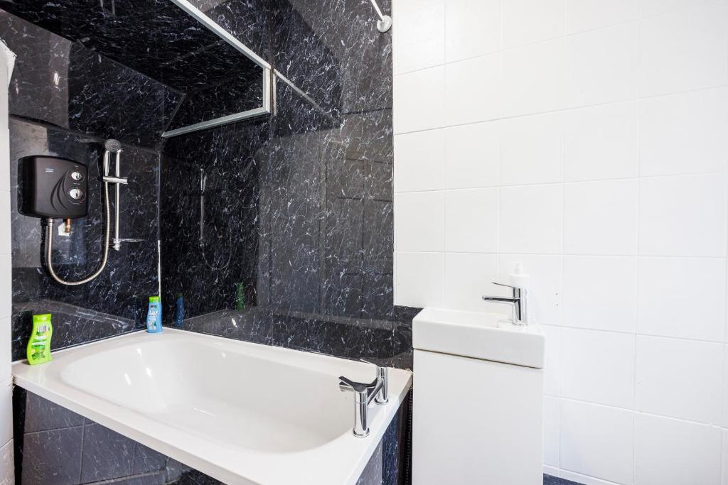 a bathroom with a sink and a bath tub at HeadsonBed- Croydon 4Bedrooms with Parking for the Larger groups in Hackbridge