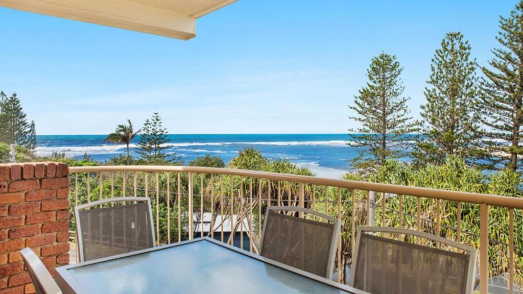balcón con mesa, sillas y vistas al océano en Unit 6 Kookaburra Court, Bulcock Beach Esplanade, en Golden Beach