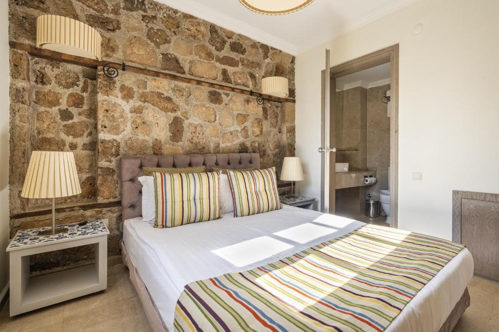 a bedroom with a bed and a stone wall at Glamorous Flat with Jacuzzi near Hadrians Gate in Antalya