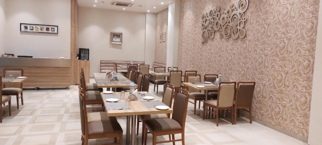 a restaurant with wooden tables and chairs and a wall at Click Hotel Bhuj in Bhuj