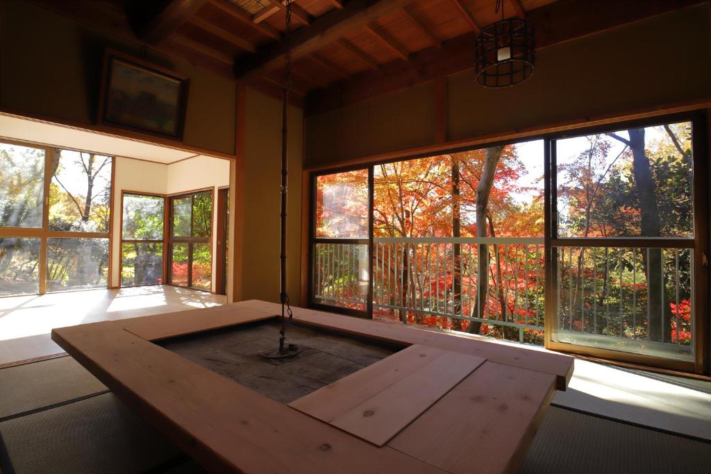 Zimmer mit einem Holztisch vor den Fenstern in der Unterkunft HAT byakugoji, Japanese traditional fireplace　HAT白毫寺　自然豊富な別荘地にある囲炉裏付き一軒家 in Nara
