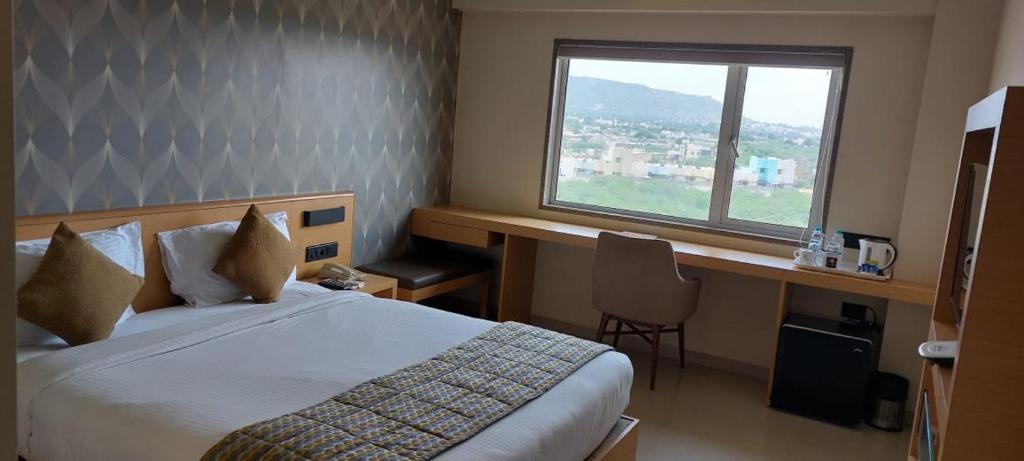 a bedroom with a bed and a desk and a window at Click Hotel Bhuj in Bhuj