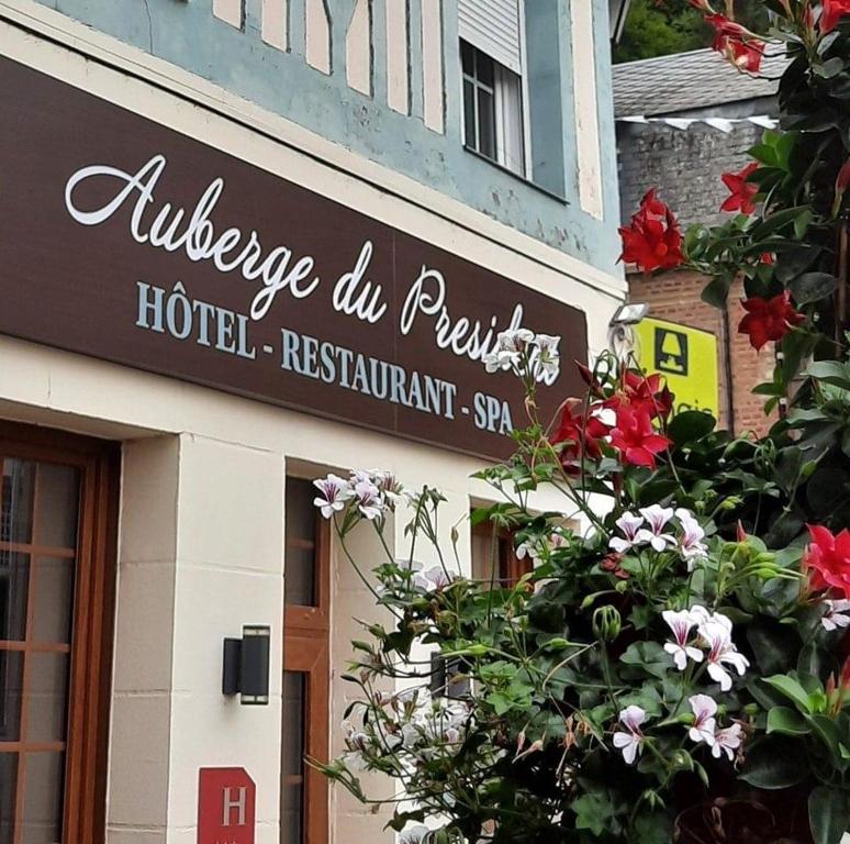 uma placa de hotel ao lado de um edifício com flores em Logis L'auberge Du President em Cormeilles