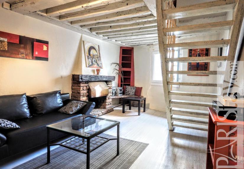 a living room with a black couch and a fireplace at Duplex 2 PIECES LA SORBONNE in Paris