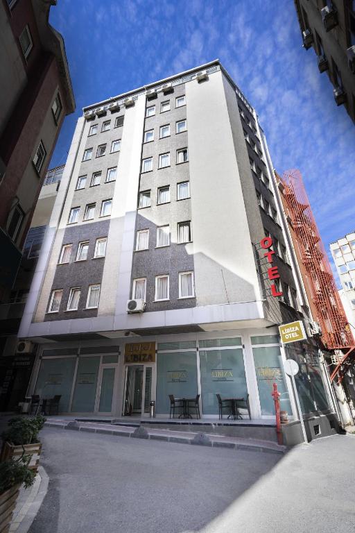 a tall white building with tables in front of it at Hotel Libiza in Gebze