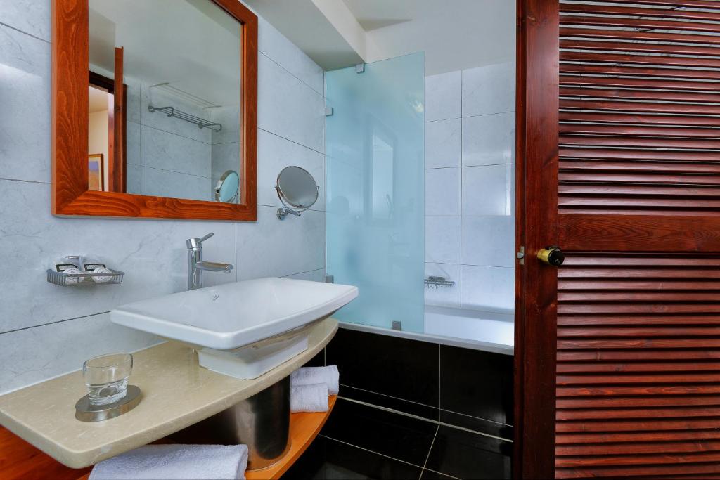 a bathroom with a sink and a mirror and a tub at Vasia Resort & Spa in Sisi
