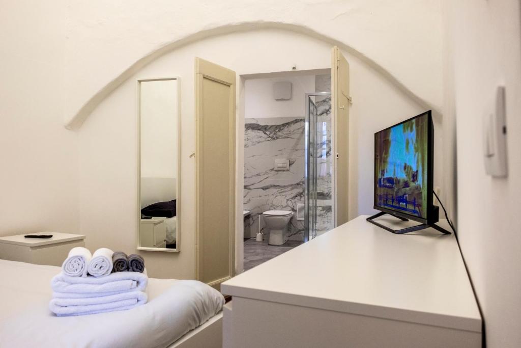 een witte kamer met een bed en een televisie bij Archivolto del Teatro in Albenga