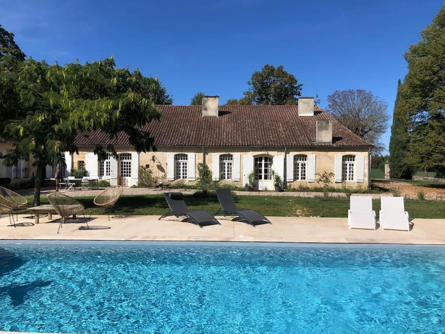 una casa con sillas y una piscina frente a ella en la Chartreuse du Domaine de la Graulet en Bergerac