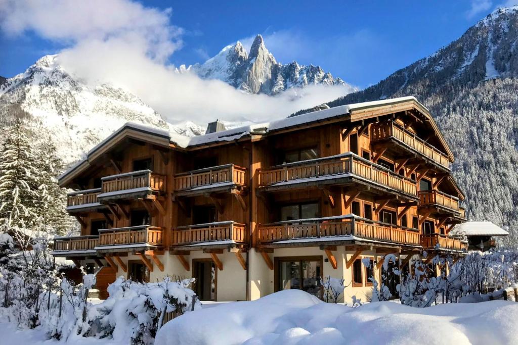 un rifugio nella neve con montagne sullo sfondo di Coin des Drus Apartment - Chamonix All Year a Chamonix-Mont-Blanc