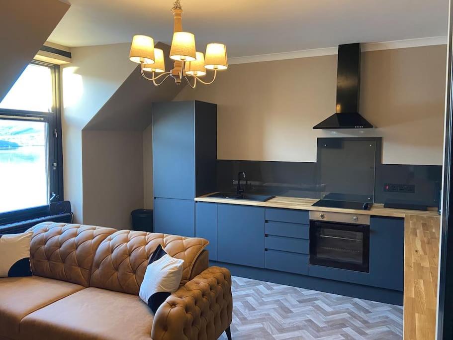 a living room with a couch and a kitchen at AK Lochview Apartment in Fort William