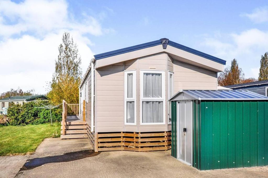 uma pequena casa branca com uma garagem verde em Spacious Stunning Lakeside 3 bed Holiday Home em Northampton
