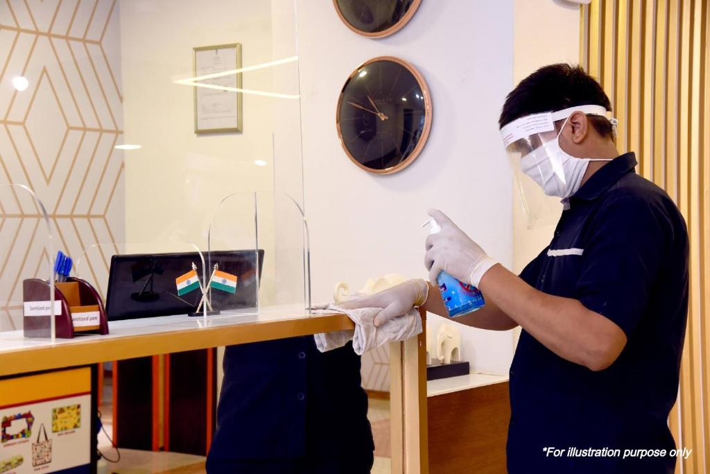 een man in een kamer met een masker en handschoenen bij SPOT ON Hotel The Annie in Bilāspur