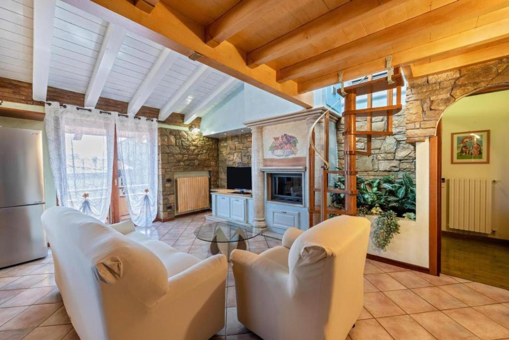 a living room with white chairs and a stone wall at Casa Vacanze Baccolo in Polpenazze del Garda