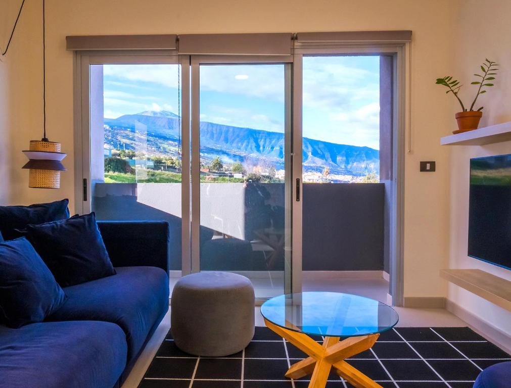 a living room with a blue couch and a glass table at 3BR Home - Teide Views Balcony - Wifi in La Orotava