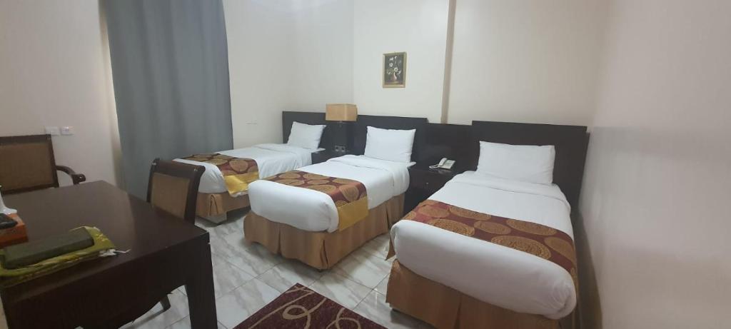 a hotel room with three beds and a desk at Durrat Mina Hotel in Mecca