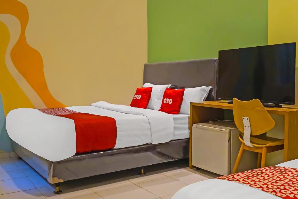 1 dormitorio con 1 cama con almohadas rojas y TV en SUPER OYO 92271 Orienchi 3 en Tangerang