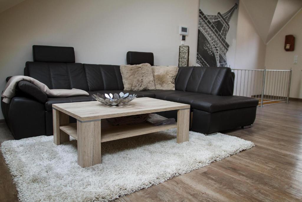 a living room with a black couch and a coffee table at Ferienhaus Saar-Traum in Saarburg