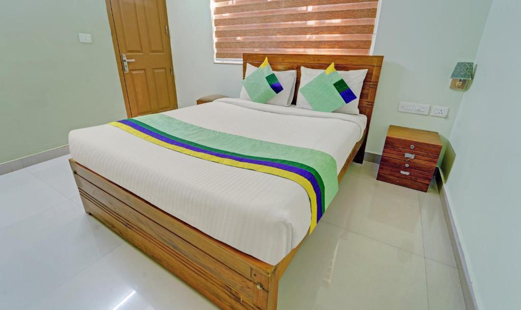 a bedroom with a bed with a colorful blanket on it at Treebo Trend Sreepathi Nirmalyam 1 Km From Guruvayoor Railway Station in Guruvāyūr