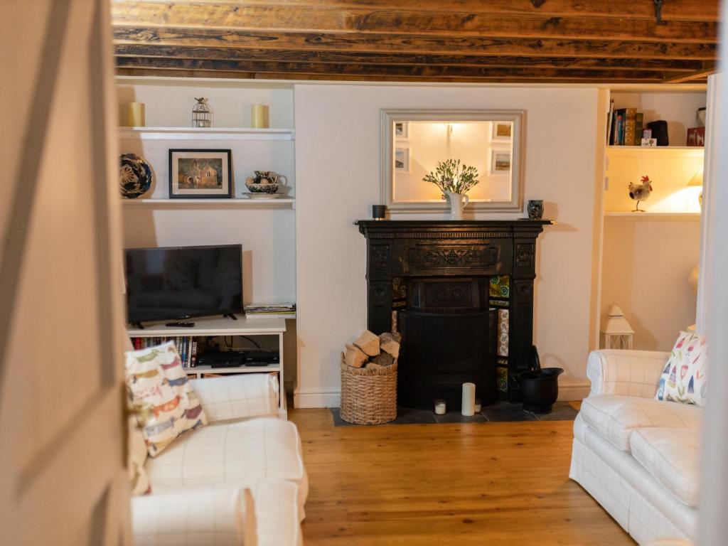 una sala de estar con chimenea y muebles blancos. en Pass the Keys Character country cottage with scenic castle views, en Llandeilo