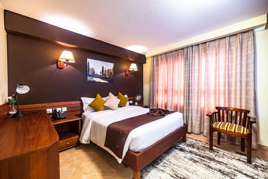 um quarto de hotel com uma cama grande e uma secretária em Samra Hotel em Nairobi