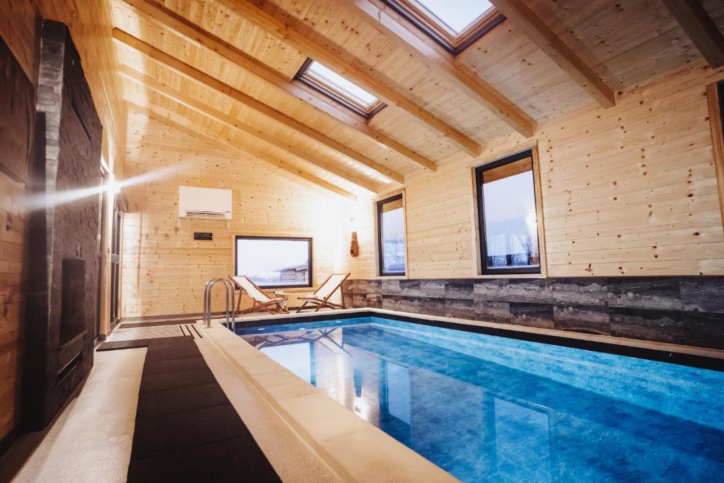 a swimming pool in a house with wooden ceilings and windows at Holiday Home Nightswim Inn in Vrbovec