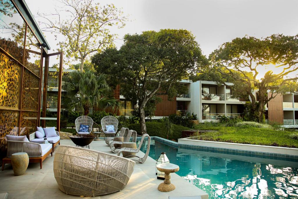 um pátio com cadeiras e uma piscina em Wyndham Ilhabela Casa Di Sirena em Ilhabela