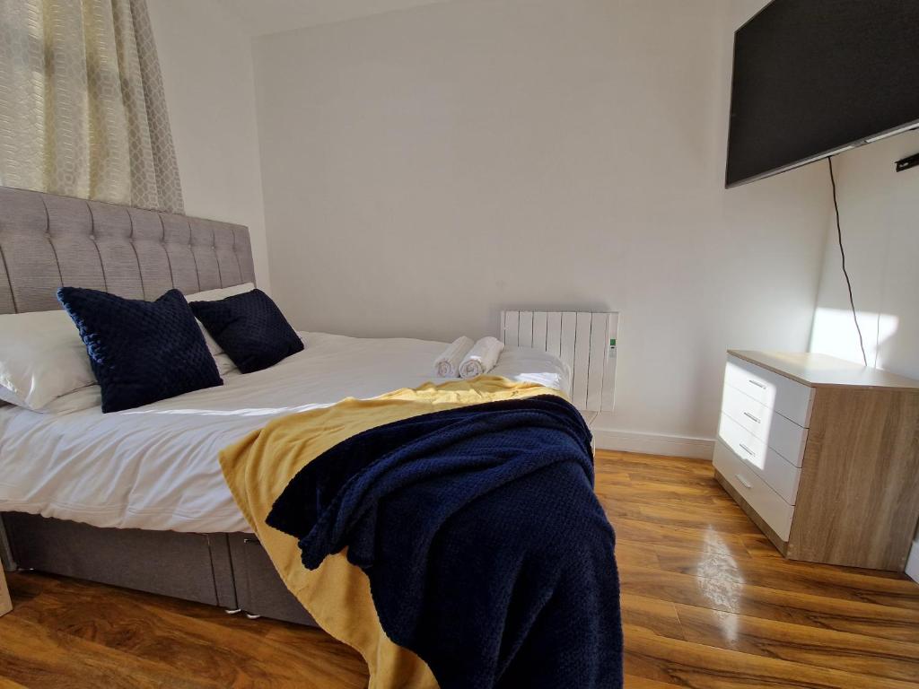a bedroom with a bed with blue pillows and a television at Flat 5. Modern studio apartment, Tynte Hotel, Mountain Ash in Quakers Yard