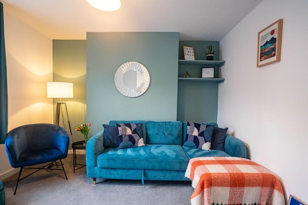 ein Wohnzimmer mit einem blauen Sofa und einem Stuhl in der Unterkunft The Becket - Three Bedroom City Centre House with Parking in Canterbury