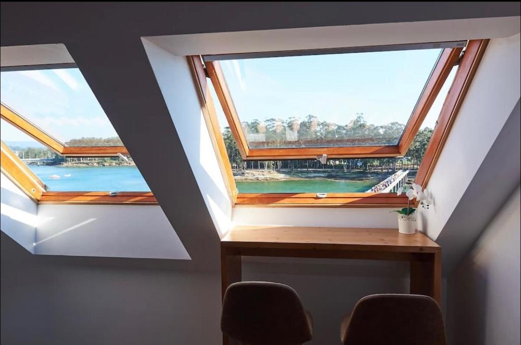 2 ventanas en una habitación con mesa y sillas en Exclusivo ático boutique con vistas al mar, en Villanueva de Arosa