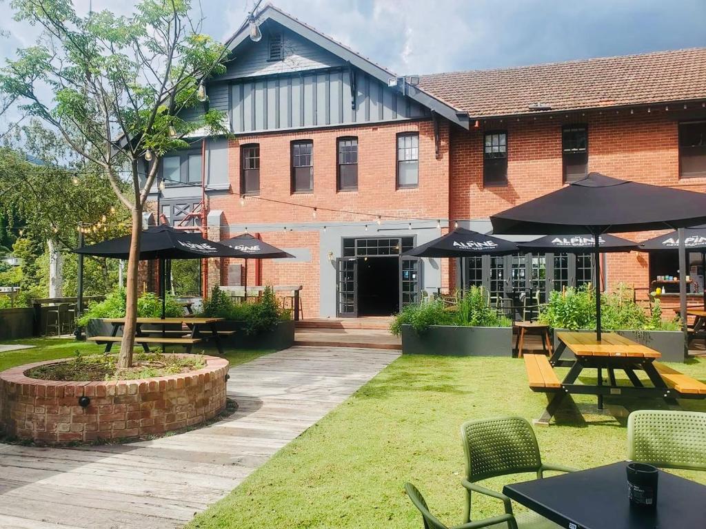 Alpine Hotel, Eat Drink Sleep في واربورتون: فناء به طاولات ومظلات أمام المبنى