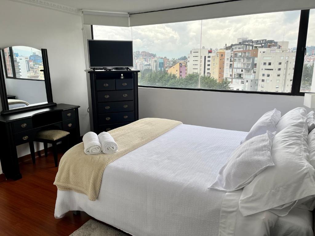 um quarto com uma cama, uma secretária e uma janela em Suite amoblada con aparcamiento privado excelente vista y ubicación! Sector La Carolina em Quito