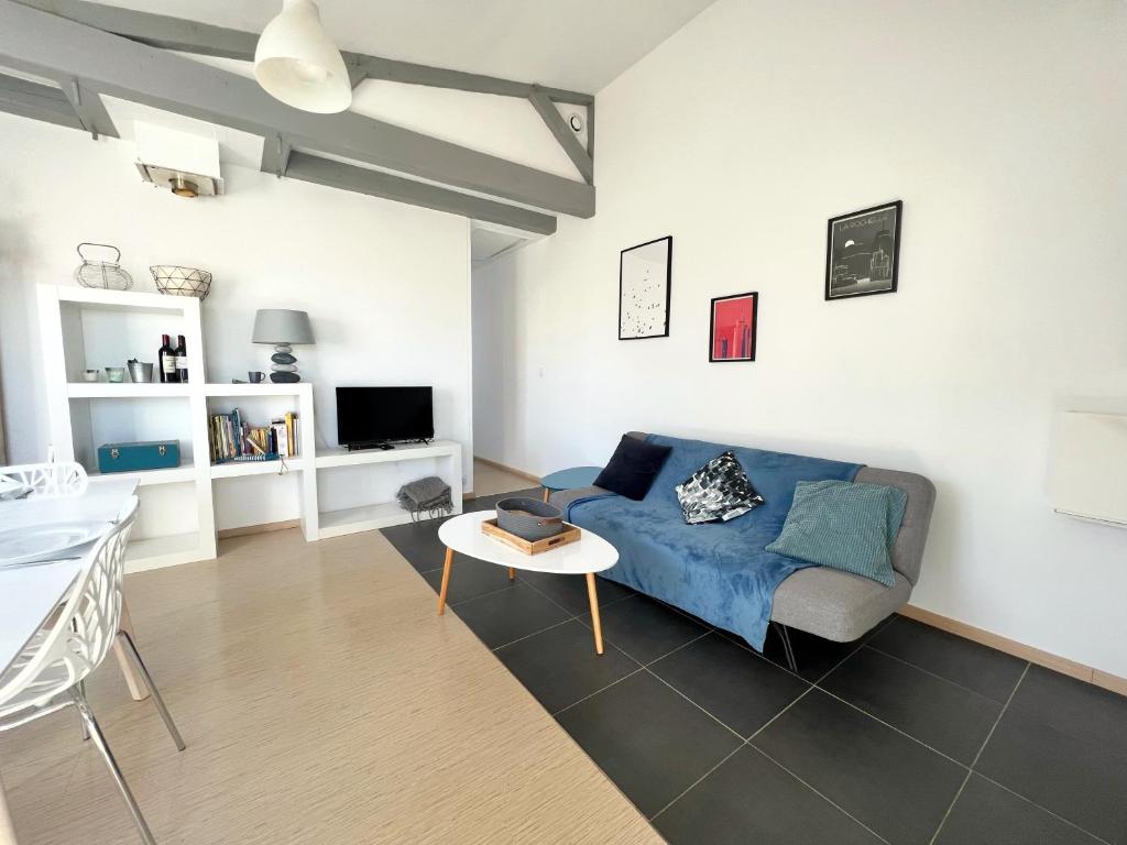 a living room with a blue couch and a table at La Petite Échappée - Proche mer in La Genilliere