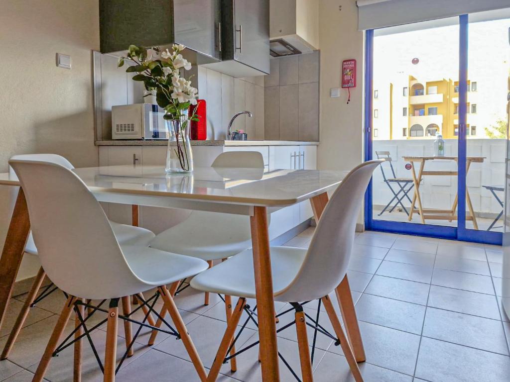 eine Küche mit einem Tisch mit weißen Stühlen und einer Vase aus Blumen in der Unterkunft Apart PRAIA DA ROCHA - AC - WIFi - BY BEDZY in Portimão