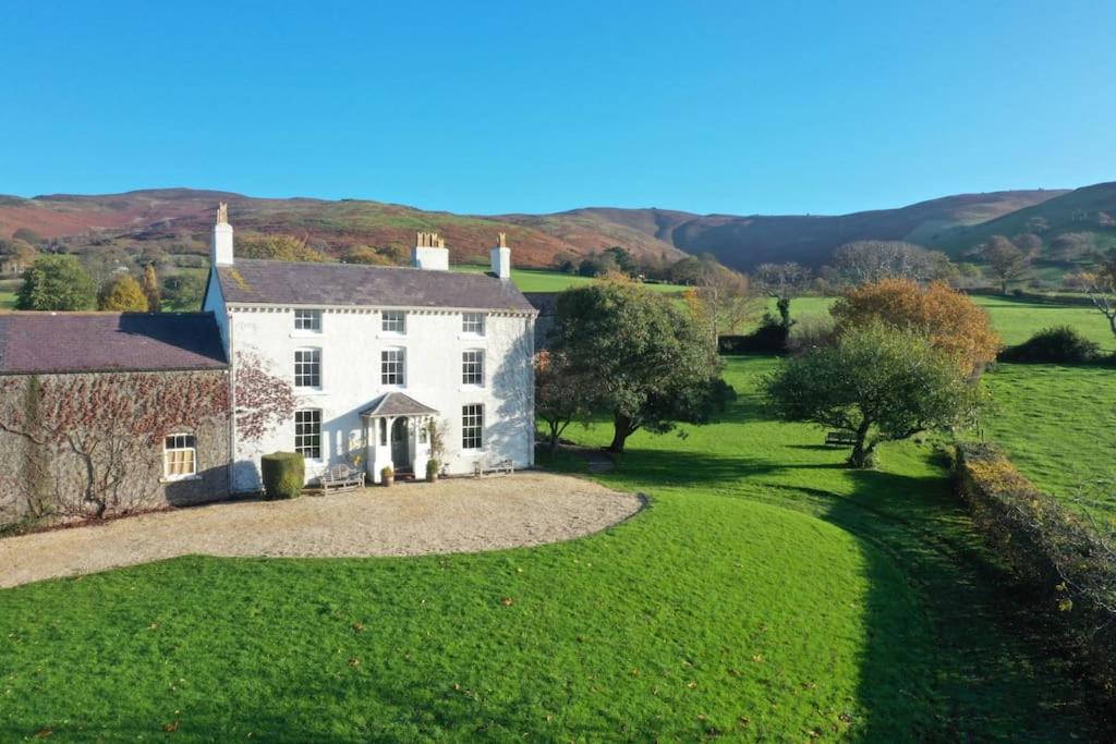 a large white house in a green field at Georgian Country House -Panoramic Views -Sleeps 12 in Ruthin