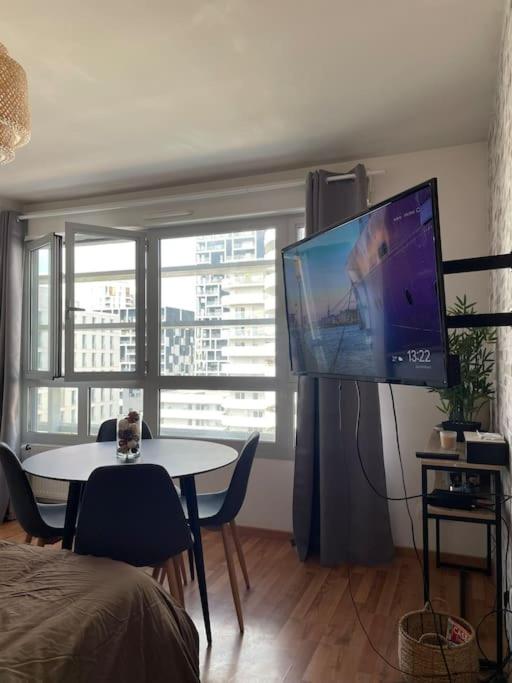 a living room with a table and a large screen tv at Appartement en Hypercentre proche Gare Sud in Nantes