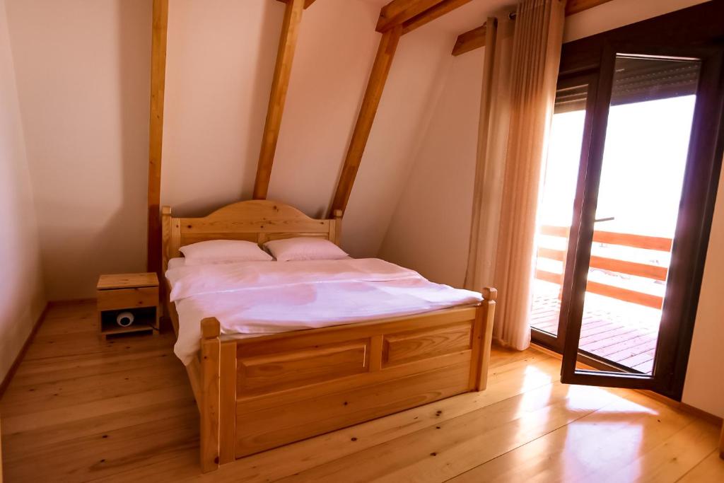 ein Schlafzimmer mit einem Holzbett in einem Zimmer mit einem Fenster in der Unterkunft HILL VIEW Chalets in Žabljak