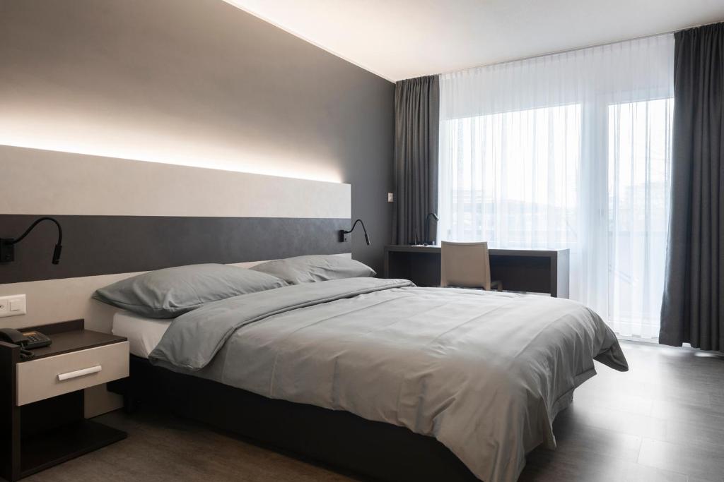 a bedroom with a large bed and a large window at Hotel Bahnhof Zollikofen in Zollikofen