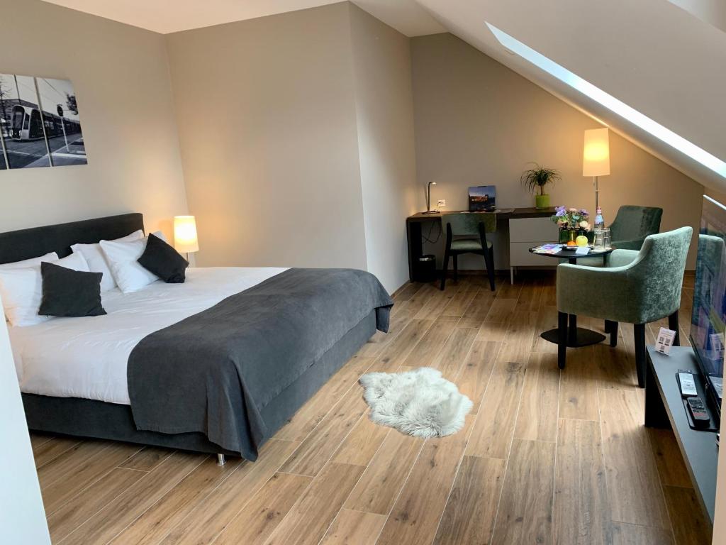 a bedroom with a bed and a desk with a chair at Hotel Monvillage in Mondercange