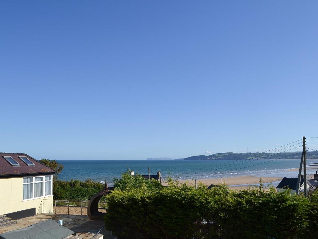 a view of a beach with a house and the ocean at Beach Cottage in Benllech