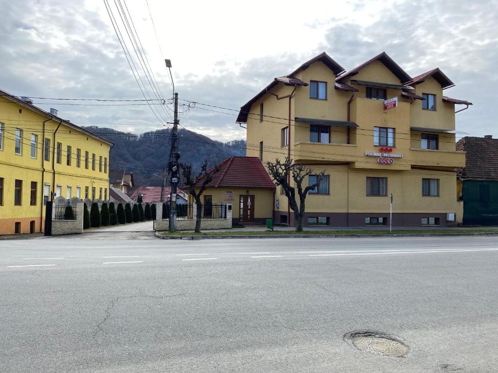 un edificio amarillo al lado de una calle en Pensiunea COCO en Năsăud