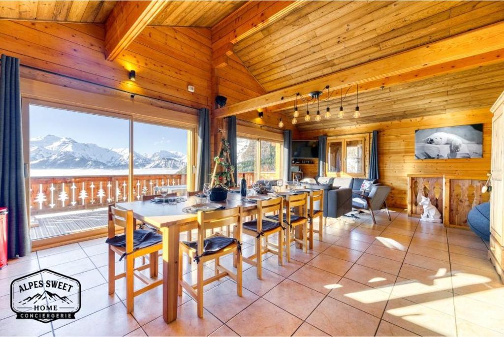 a dining room with a long table and a large window at Alpes Sweet Home - Chalet en 7 in L'Alpe-d'Huez