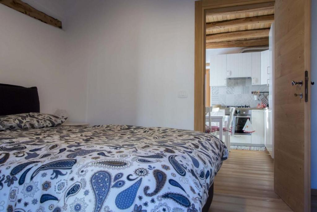 um quarto com uma cama azul e branca e uma cozinha em Casa Claudia - Casa Vacanze em Domegge di Cadore