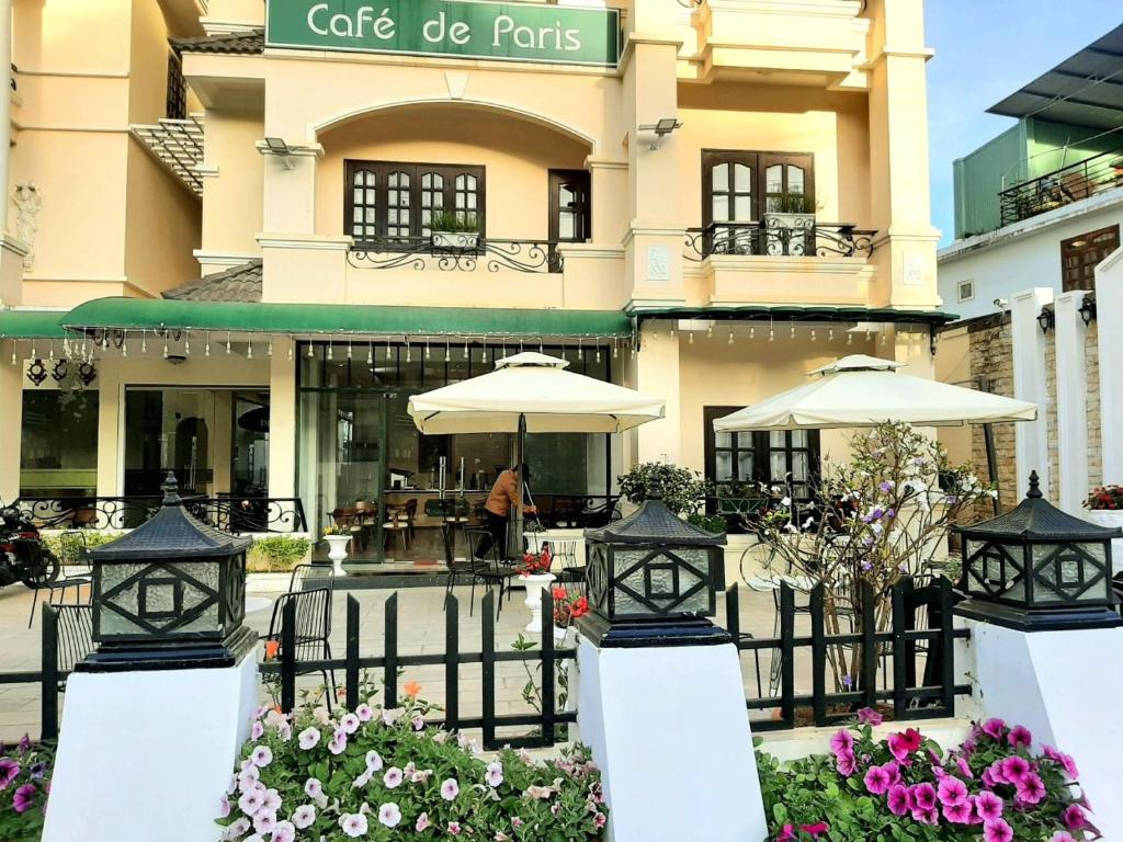 un edificio con un café hacer ollas delante de él en Le Petit Paris Dalat Hotel, en Da Lat