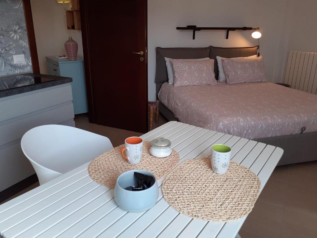 salon z łóżkiem i stołem z kubkami w obiekcie Bilocale in Lecce w mieście Lecce