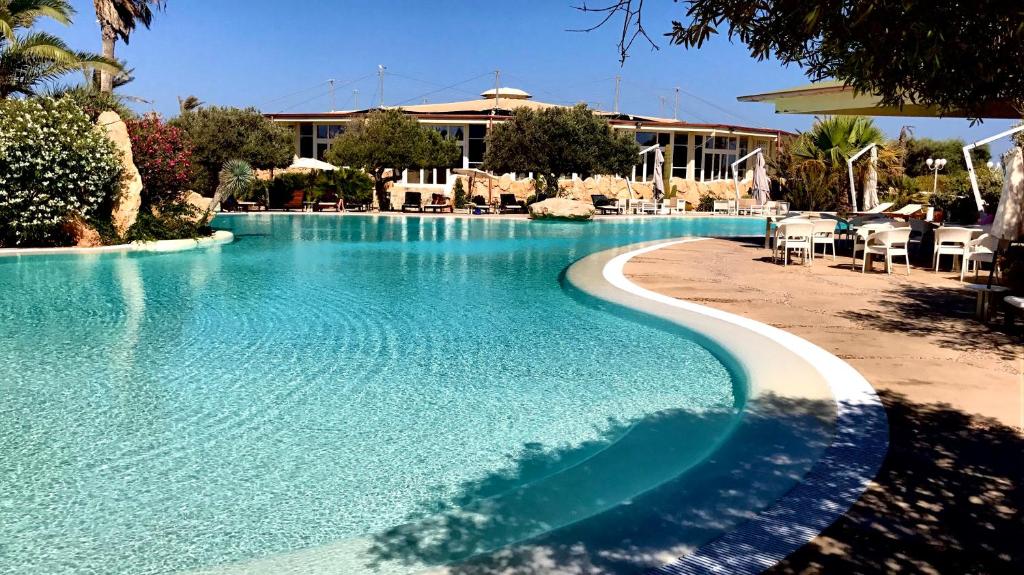 a large swimming pool with a resort in the background at Cupola Bianca Resort in Lampedusa