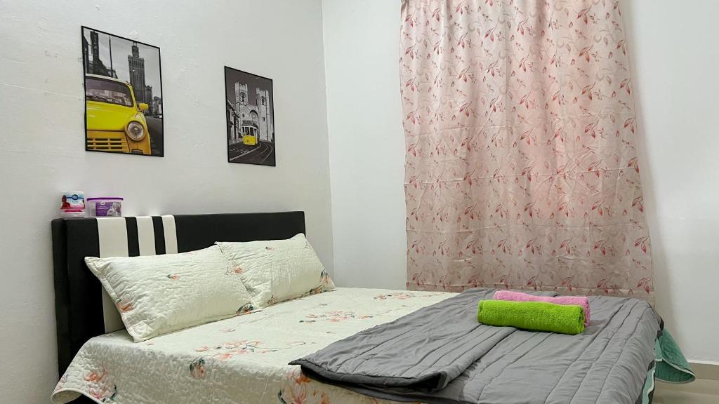 a small bedroom with a bed with a green pillow at Mahkota Aman Guest House - 5pax in Kuantan