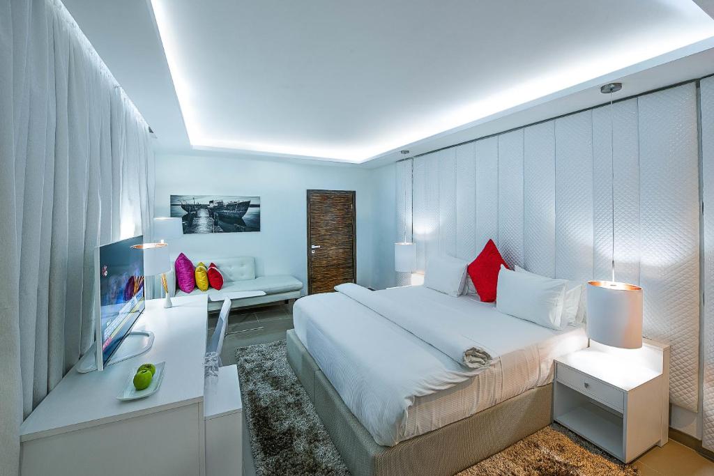 um quarto com uma grande cama branca e uma secretária em Maison Fahrenheit em Lagos